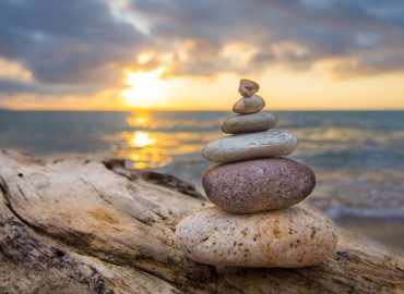 Zen Stones on a tree trunk and sunset in the background.